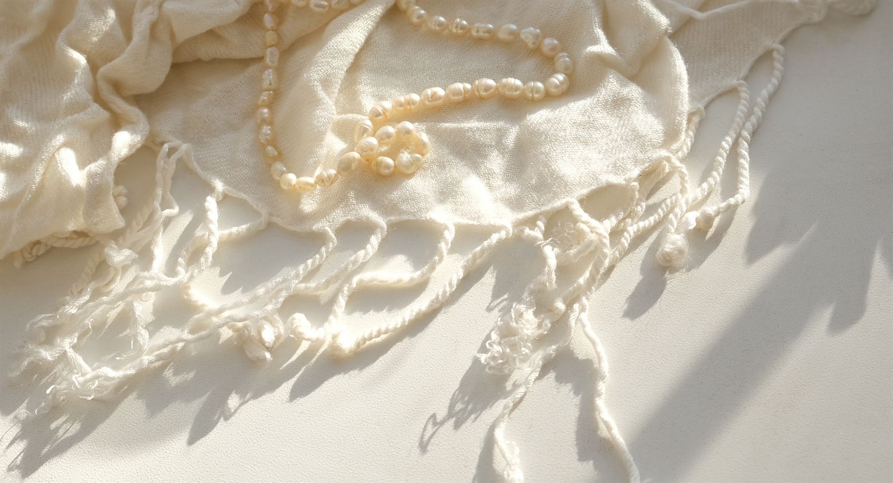 Pearls resting on white linen in soft light