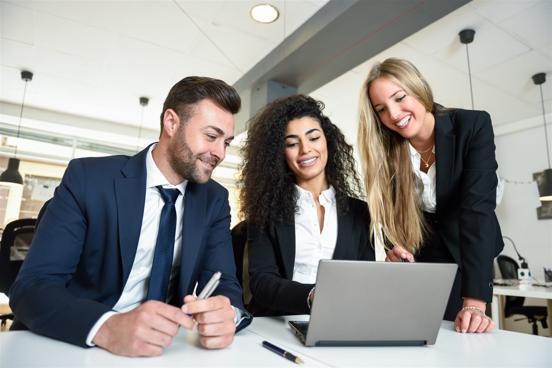 Three colleagues reviewing documents together on a laptop